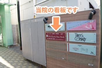 ⑤ビル入口看板に 5F MotomachiBaseBody とあります